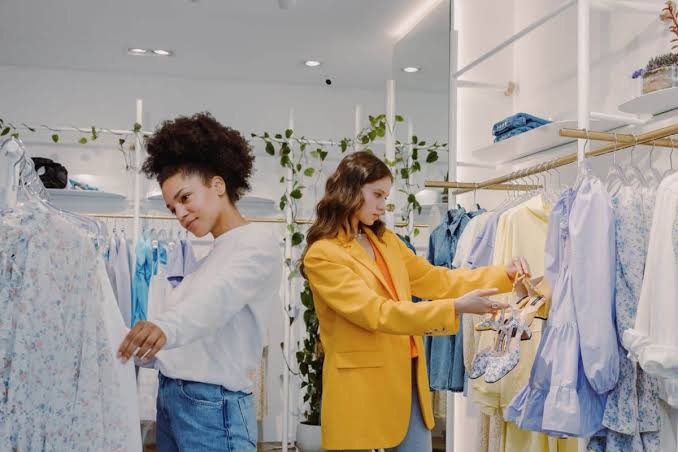 Duas clientes observando peças de roupas em uma loja