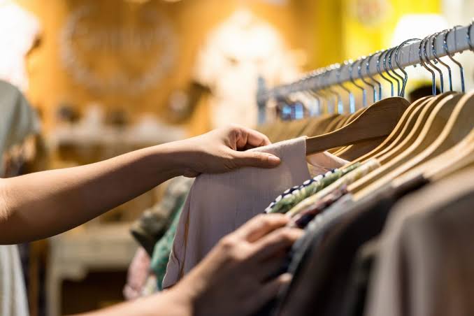 Pessoa escolhendo uma peça de roupa em uma arara